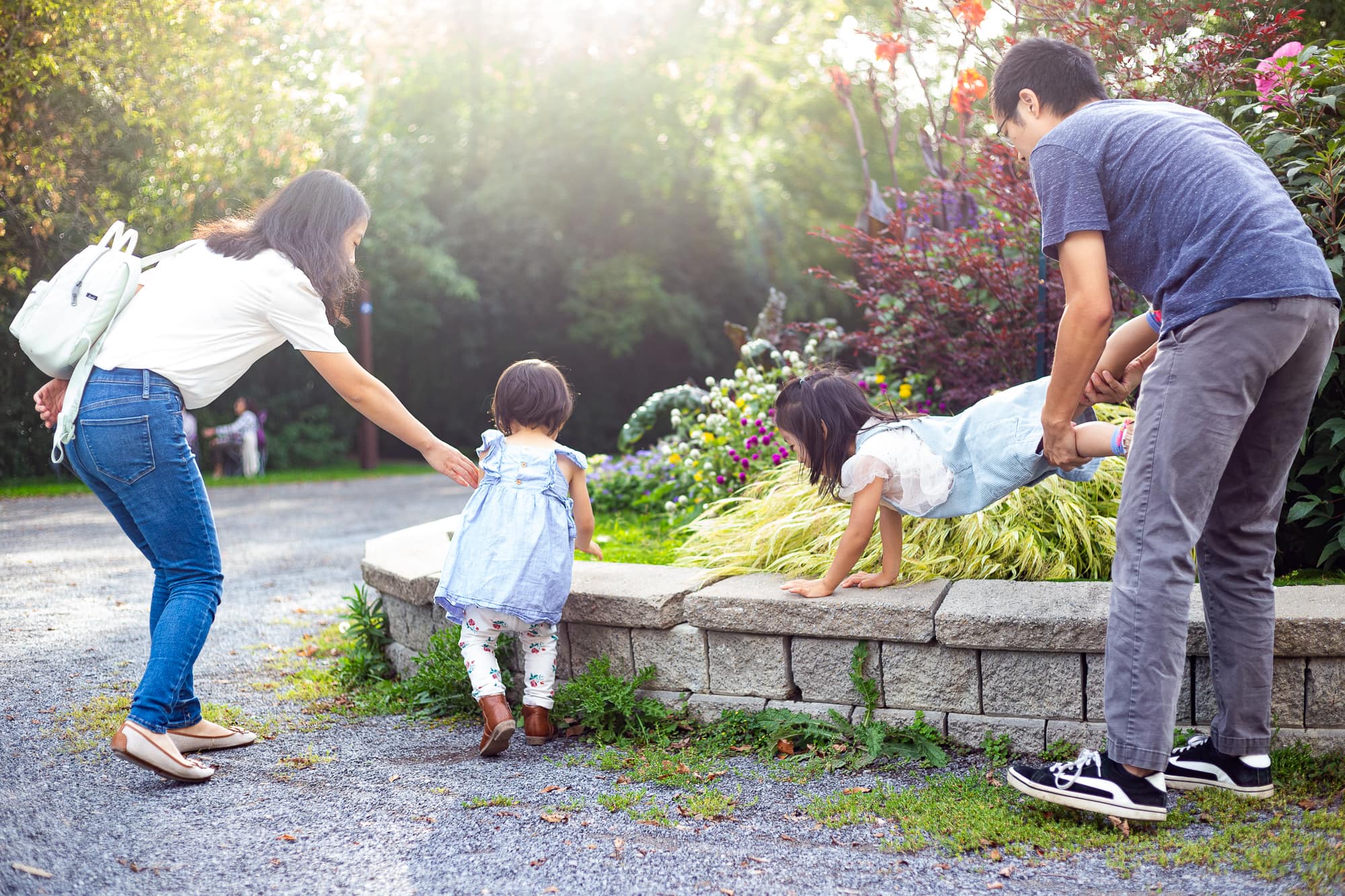 filles jouant à la brouette sur une bordure avec son père, mère et soeur à côté